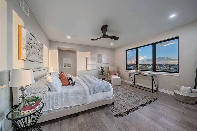 Modern bedroom with a bed, ceiling fan, large windows, and mountain views