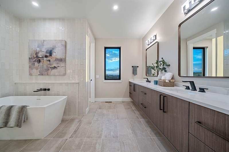 Modern spa-style bathroom with freestanding tub, double vanity, and large mirrors