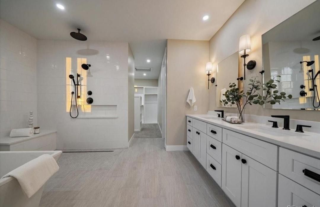 Spacious white bathroom with double vanity, soaking tub, and open walk-in shower with warm lighting.