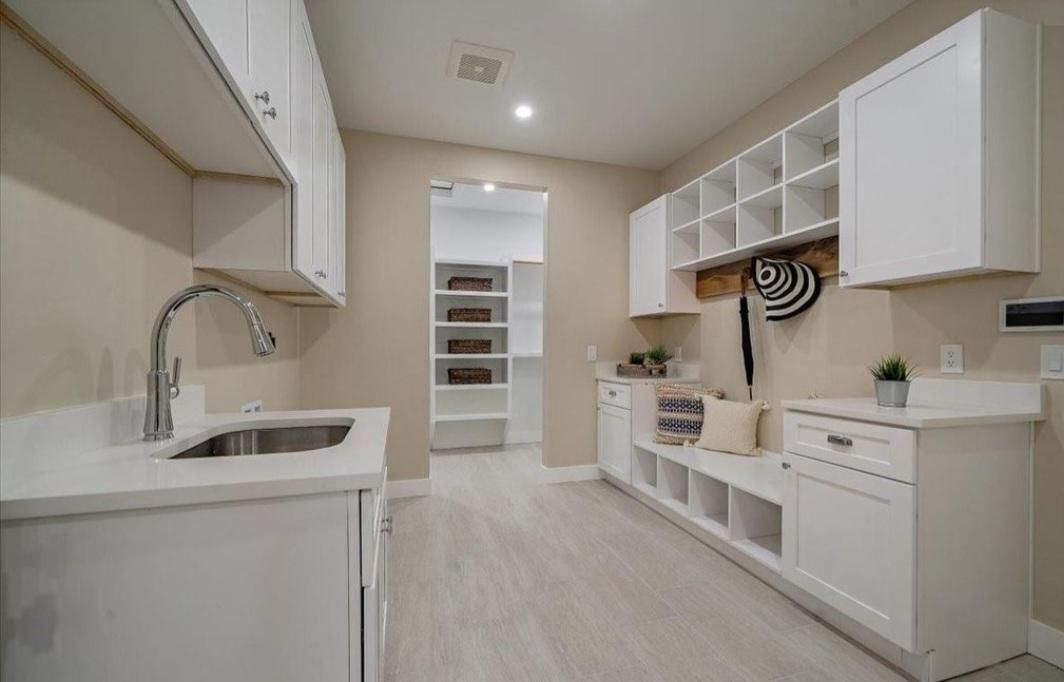 Bright modern kitchen with white cabinets, central island, and open shelving along the right wall.