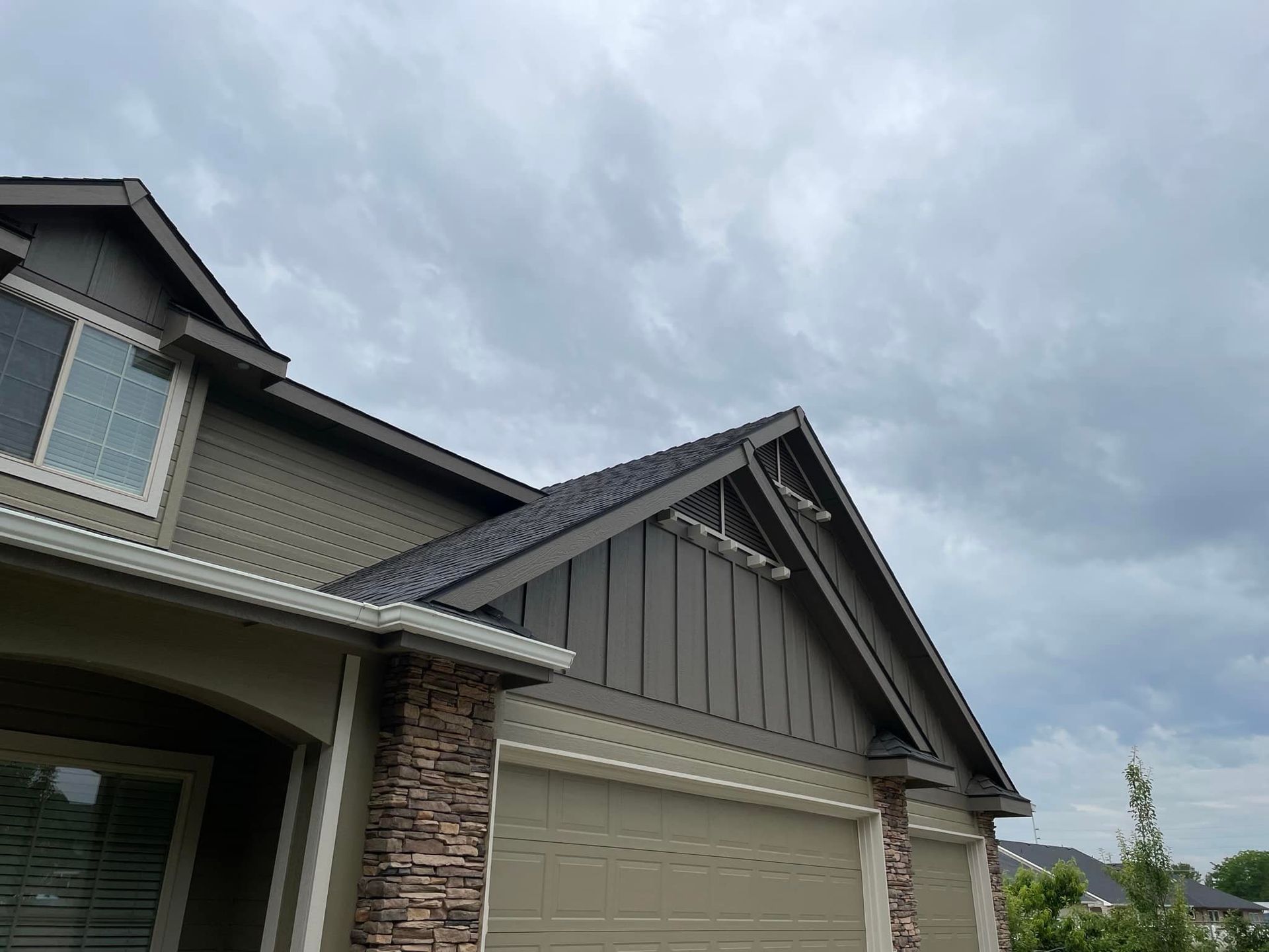 Suburban house exterior with beige garage, stone siding, and cloudy sky