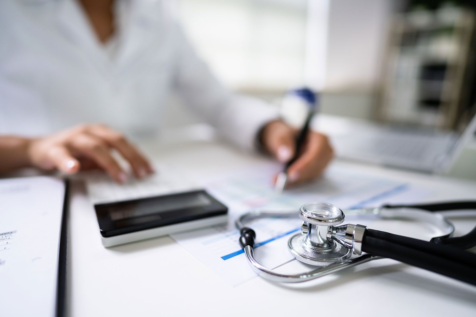 doctor writing with a stethoscope in the foreground