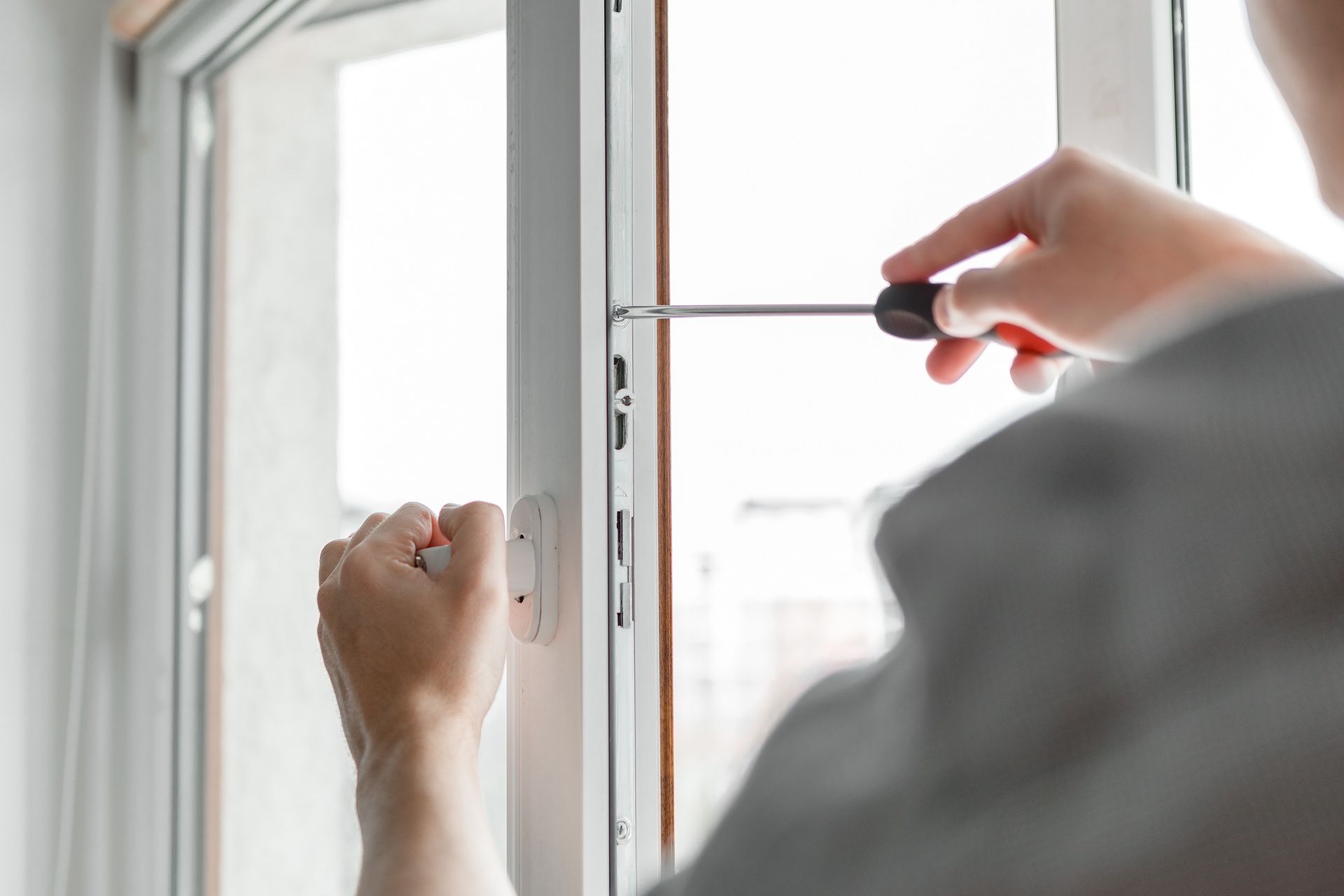 An unrecognized worker installing and checking window in a new house.