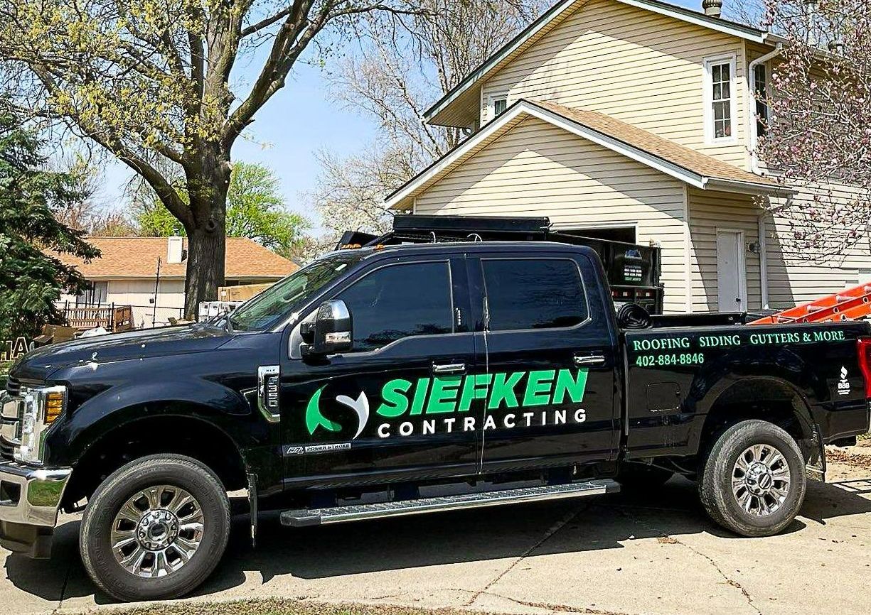 A black truck is parked in front of a house | Siefken Roofing and Remodeling Services in Omaha, NE