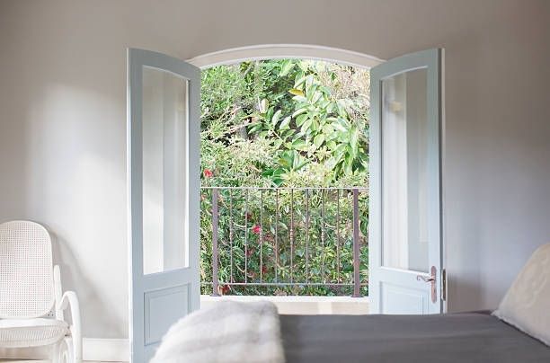 A bedroom with a bed , chair , and a balcony | Siefken Roofing and Remodeling Services in Omaha, NE