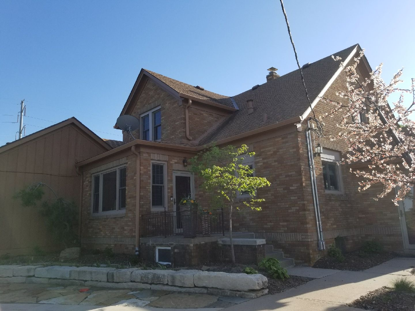 A brick house with a brown roof and a tree in front of it  | Roofing Projects | Siefken Roofing and Remodeling Services in Omaha, NE
