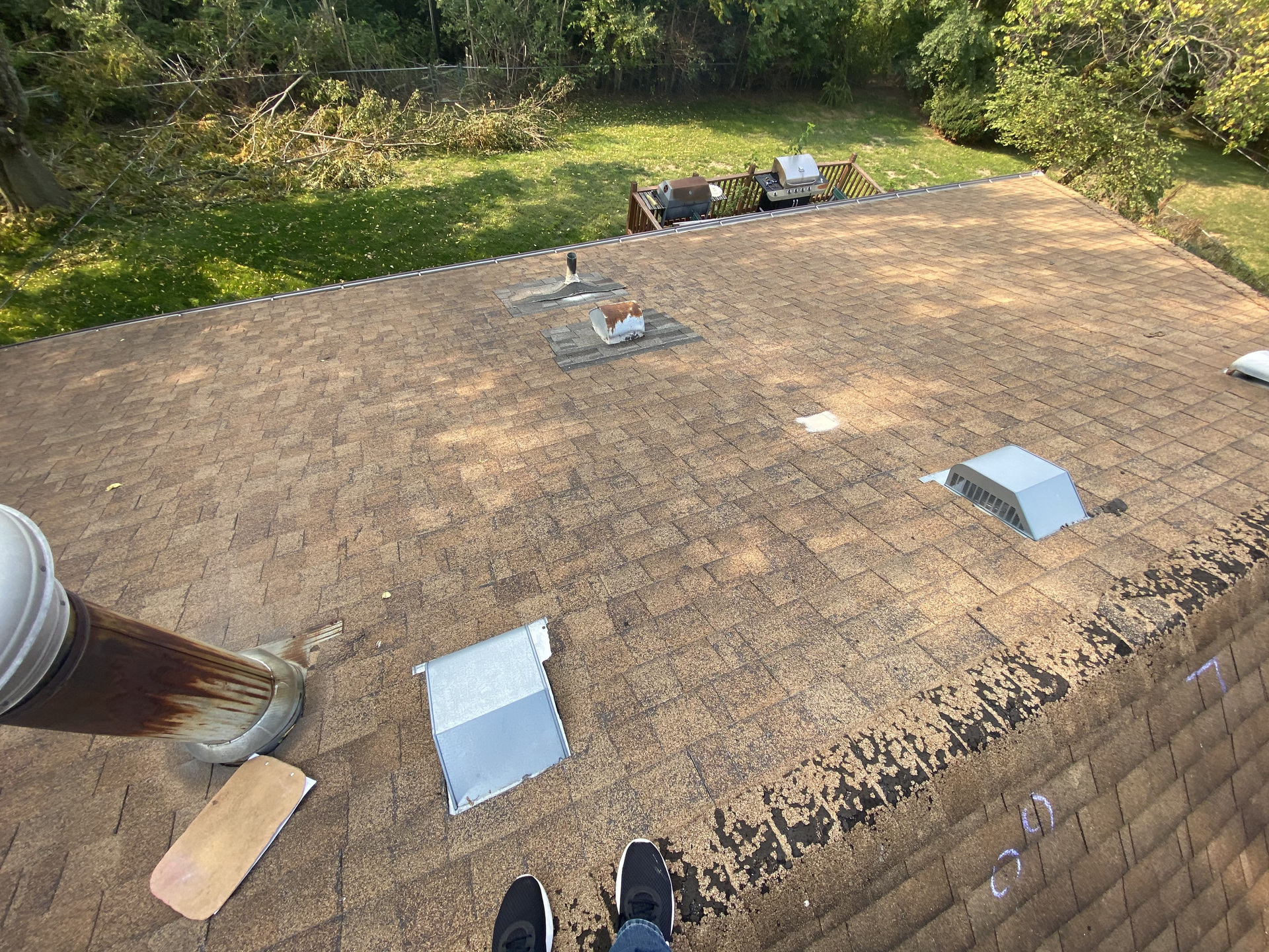 A person is painting the roof of a house with a brush | Roofing Projects | Siefken Roofing and Remodeling Services in Omaha, NE