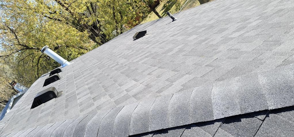 A close up of a roof with a chimney and trees in the background | Roofing Projects | Siefken Roofing and Remodeling Services in Omaha, NE