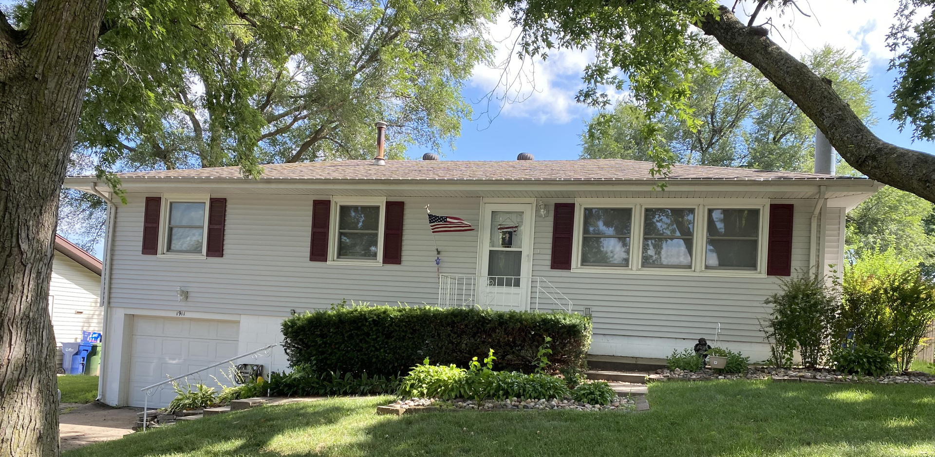 A white house with red shutters and a tree in front of it  | Roofing Projects | Siefken Roofing and Remodeling Services in Omaha, NE