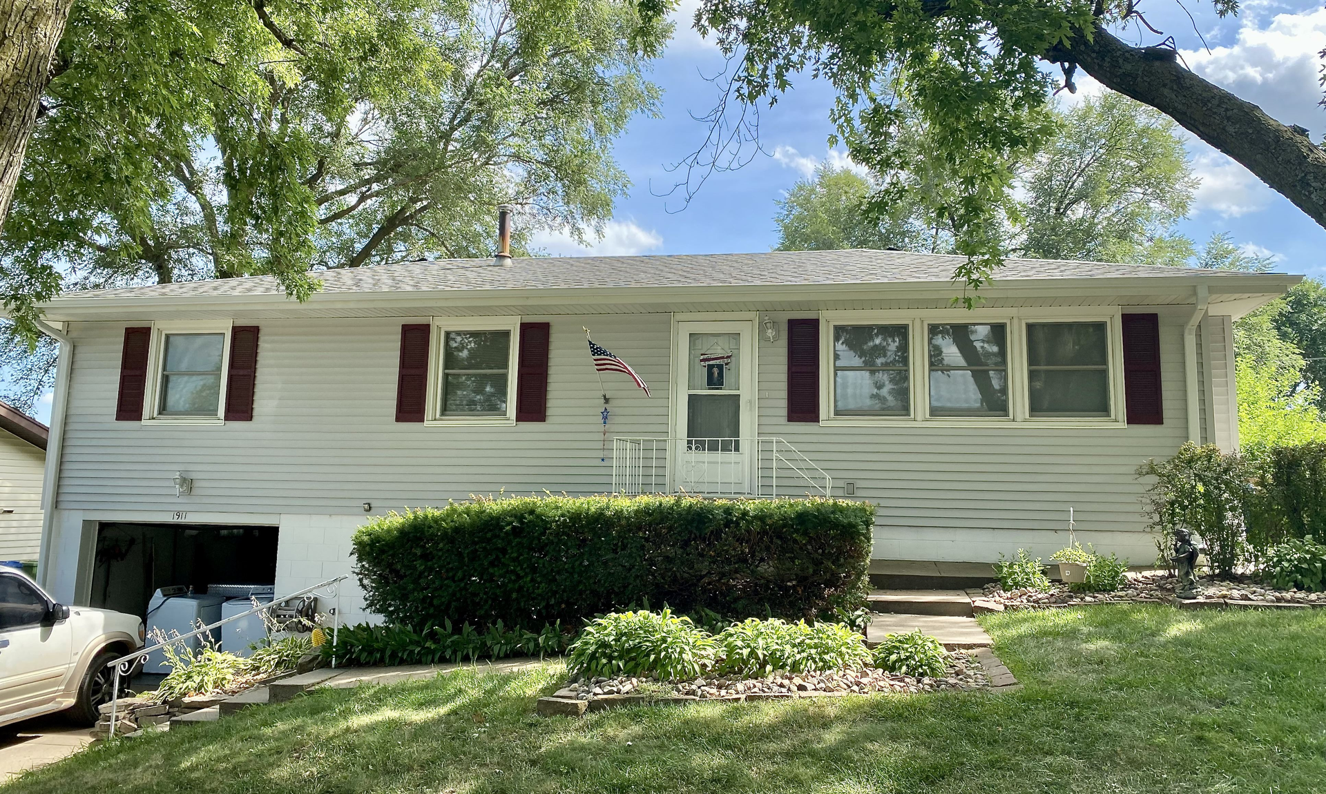 A white house with red shutters and a car parked in front of it | Roofing Projects | Siefken Roofing and Remodeling Services in Omaha, NE