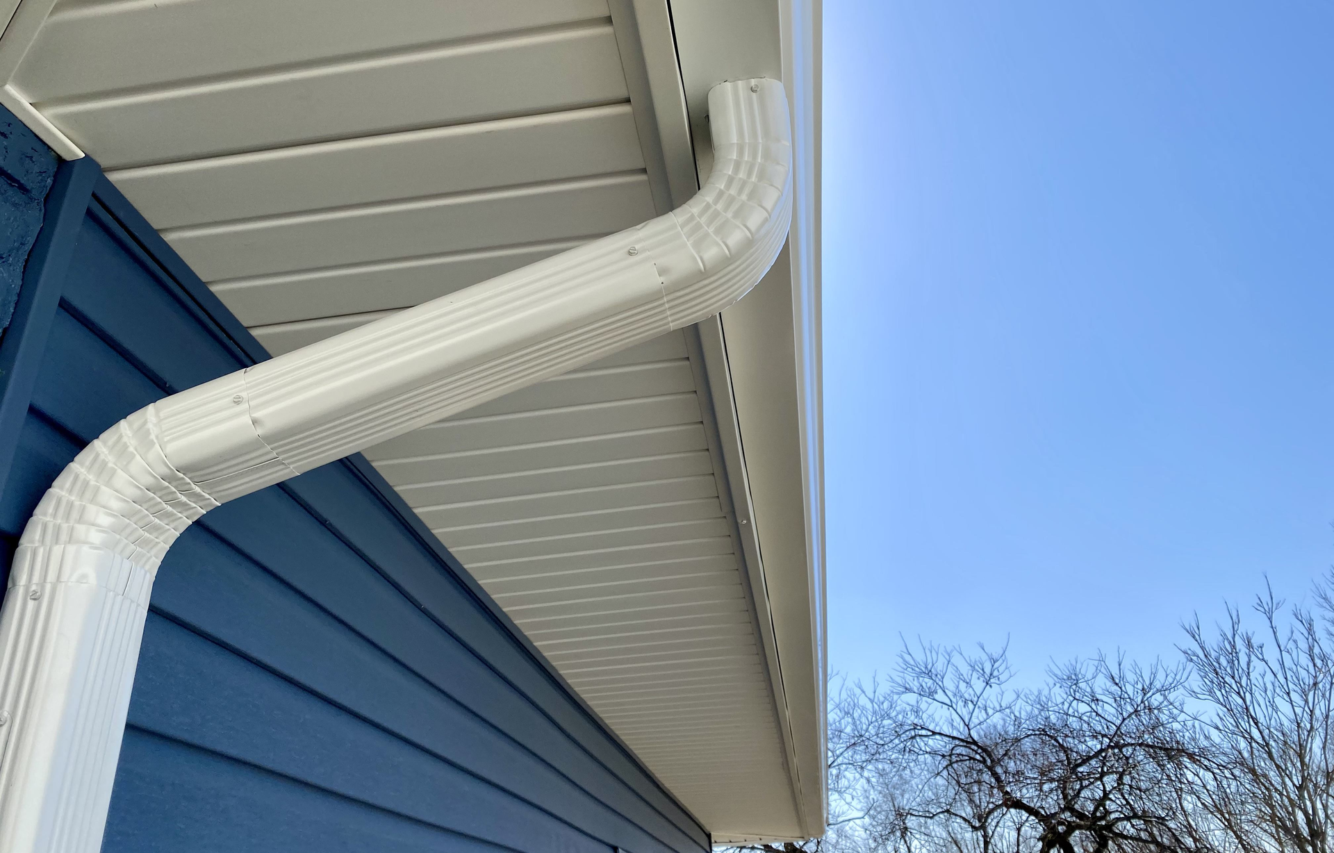 A white gutter is attached to the side of a house | Gutters Projects | Siefken Roofing and Remodeling Services in Omaha, NE