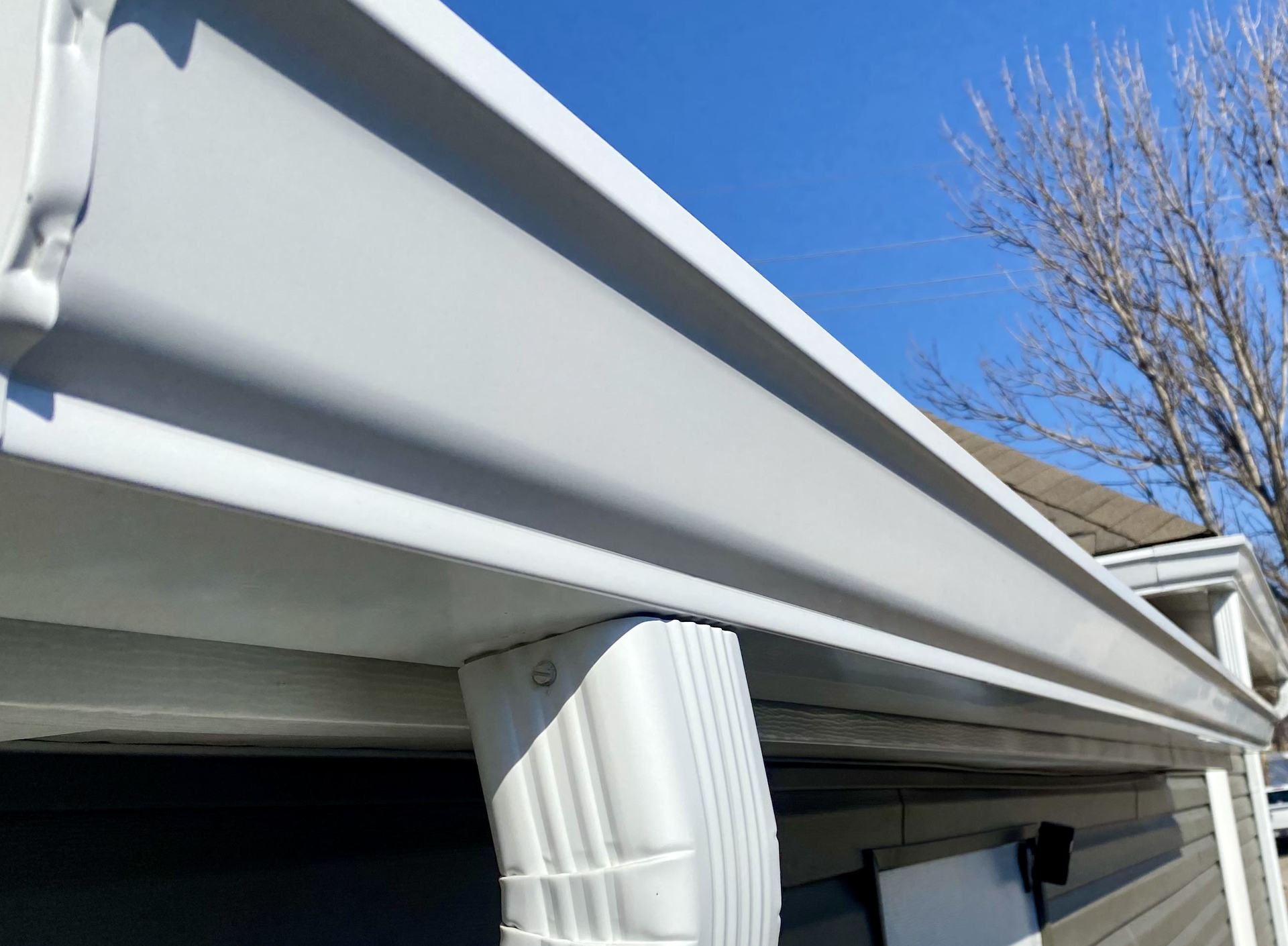 A white gutter is on the side of a house  | Gutters Projects | Siefken Roofing and Remodeling Services in Omaha, NE