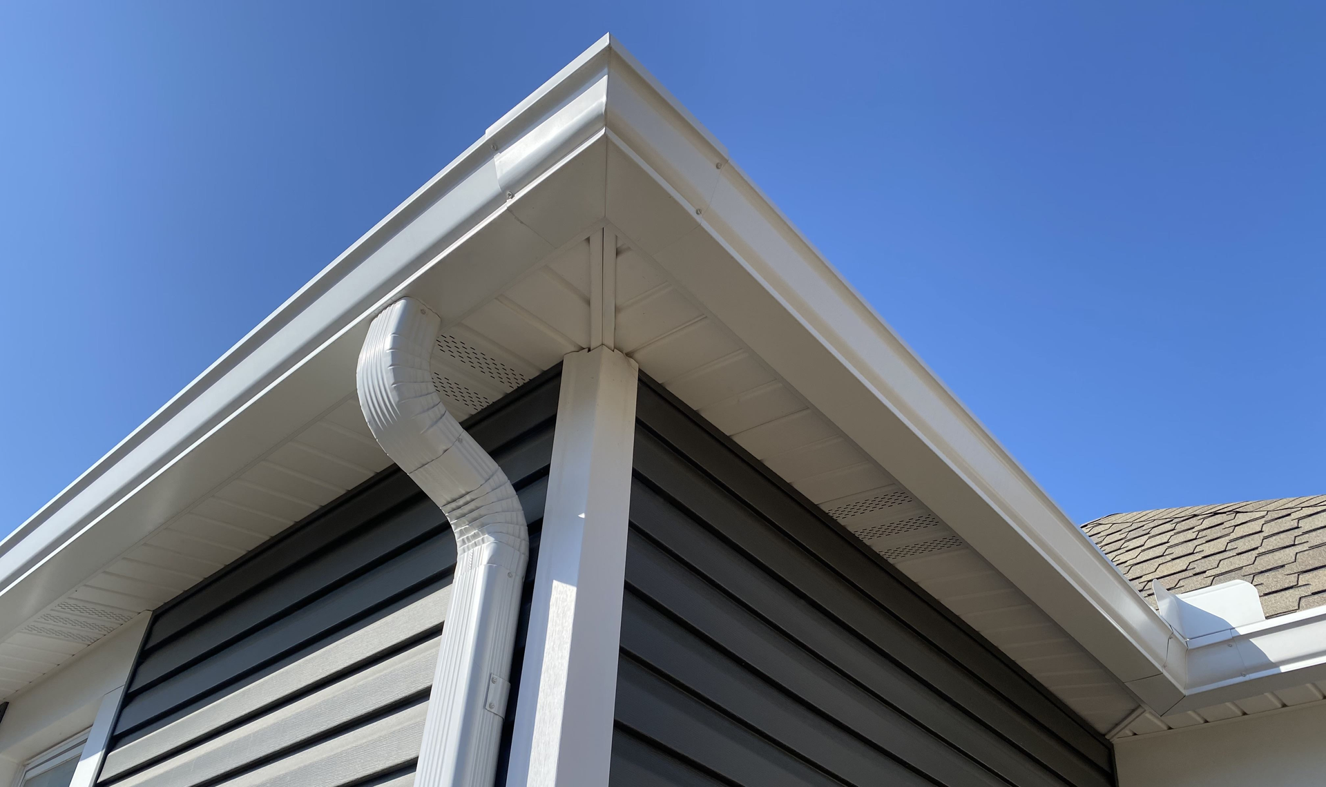 A gutter on the side of a house with a blue sky in the background  | Gutters Projects | Siefken Roofing and Remodeling Services in Omaha, NE