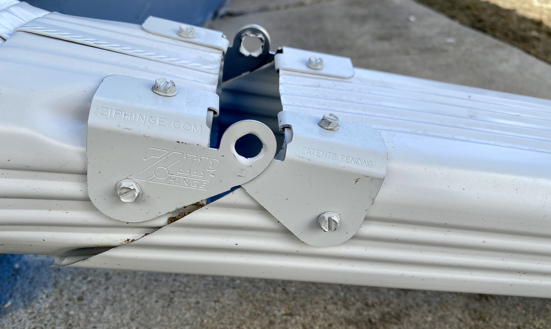 A close up of a metal bracket on a white gutter  | Gutters Projects | Siefken Roofing and Remodeling Services in Omaha, NE