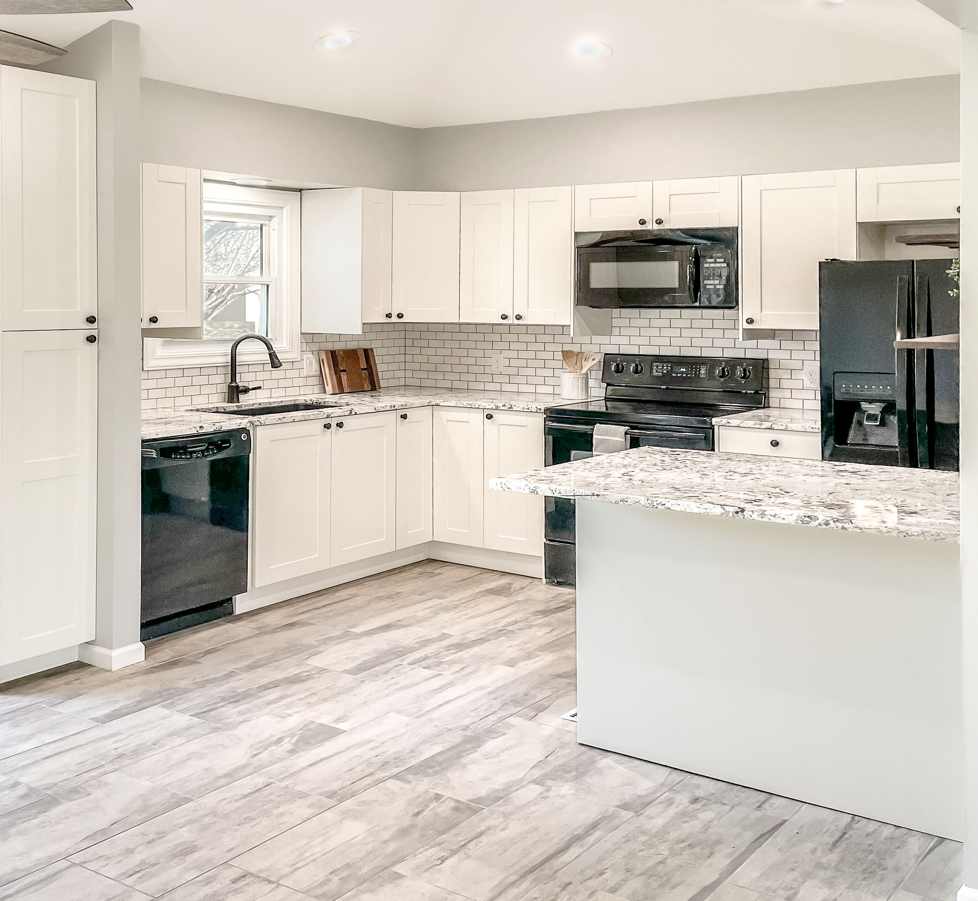 A kitchen with white cabinets , granite counter tops , black appliances and a large island | Kitchen Projects | Siefken Roofing and Remodeling Services in Omaha, NE