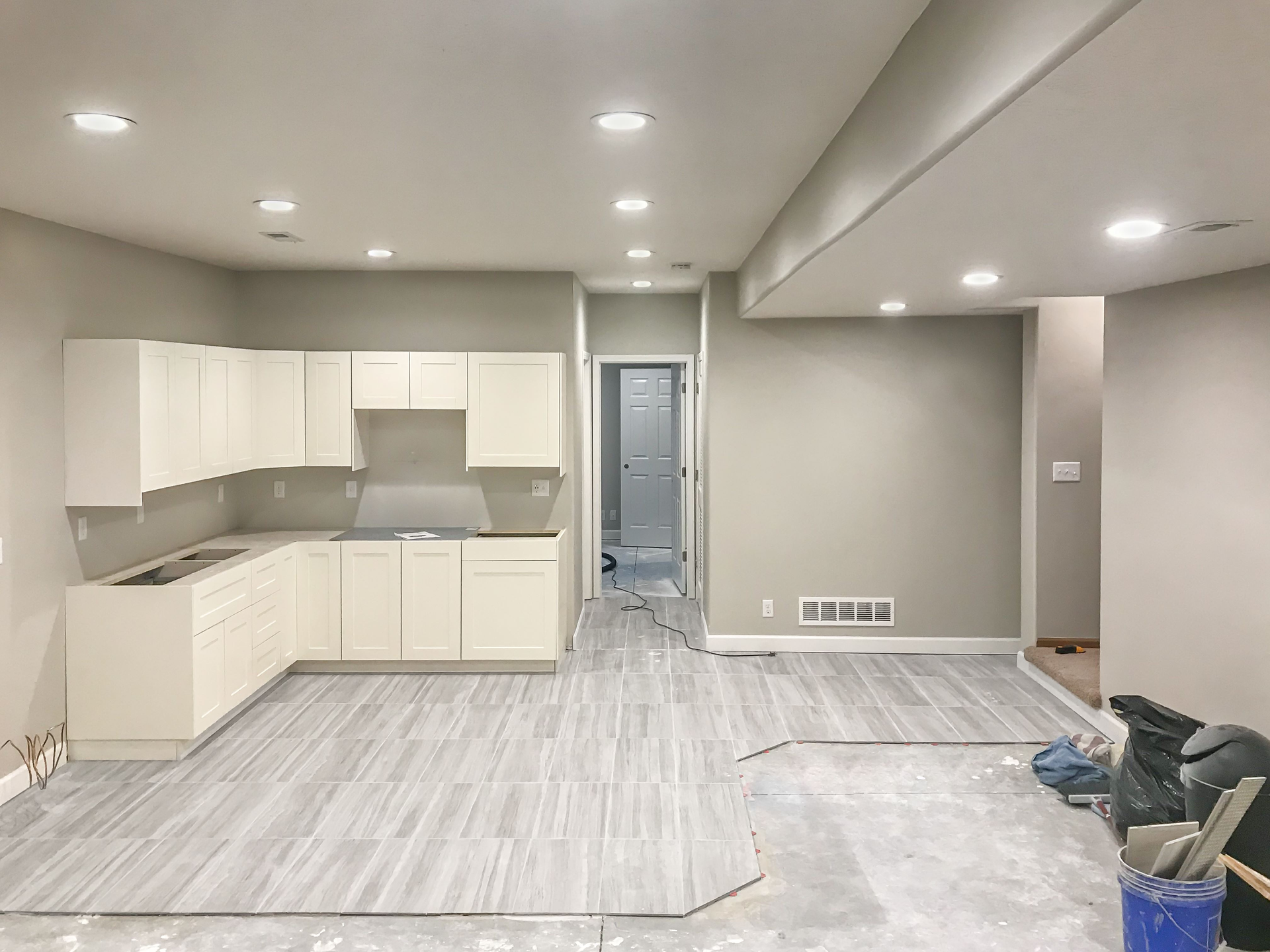An empty basement with a kitchen and a living room | Kitchen Projects | Siefken Roofing and Remodeling Services in Omaha, NE