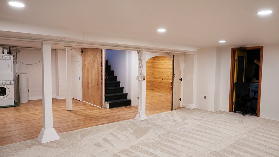 An empty basement with a staircase and a washer and dryer | Siefken Roofing and Remodeling Services in Omaha, NE