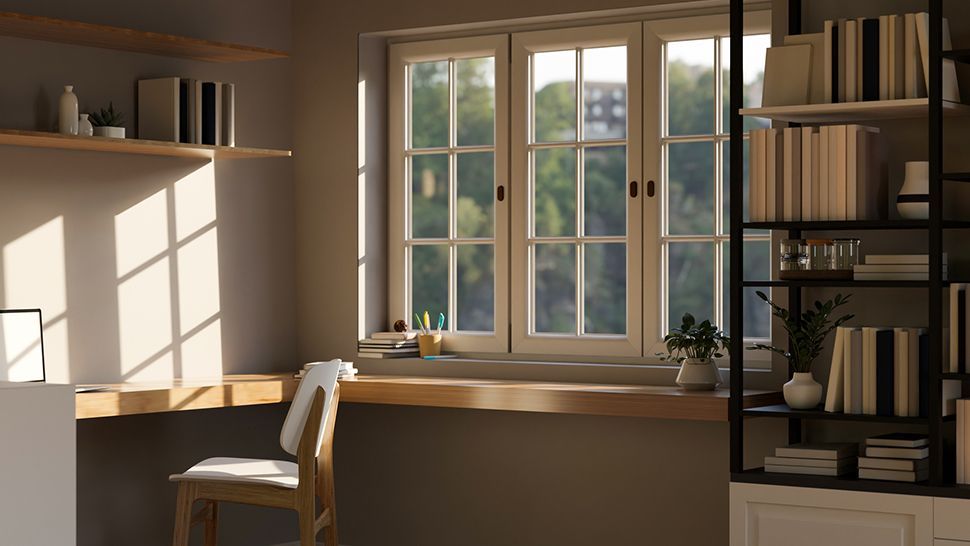 A home office with a desk , chair , bookshelf and window | Siefken Roofing and Remodeling Services in Omaha, NE