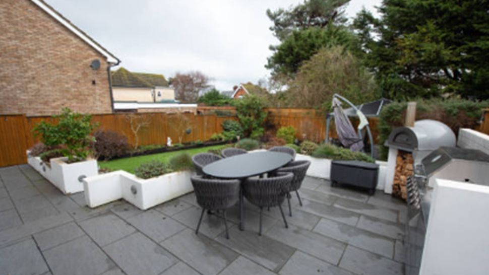 A patio with a table and chairs in a garden | Kitchen Projects | Siefken Roofing and Remodeling Services in Omaha, NE