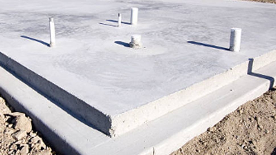 A concrete slab with pipes attached to it is sitting on top of a dirt ground | Kitchen Projects | Siefken Roofing and Remodeling Services in Omaha, NE