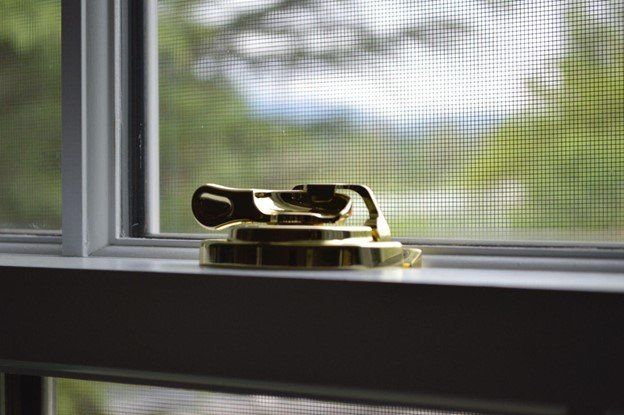 A close up of a brass window lock on a window sill | Siefken Roofing and Remodeling Services in Omaha, NE