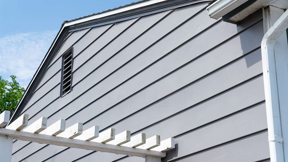 A gray house with a white pergola on the side of it | Siefken Roofing and Remodeling Services in Omaha, NE