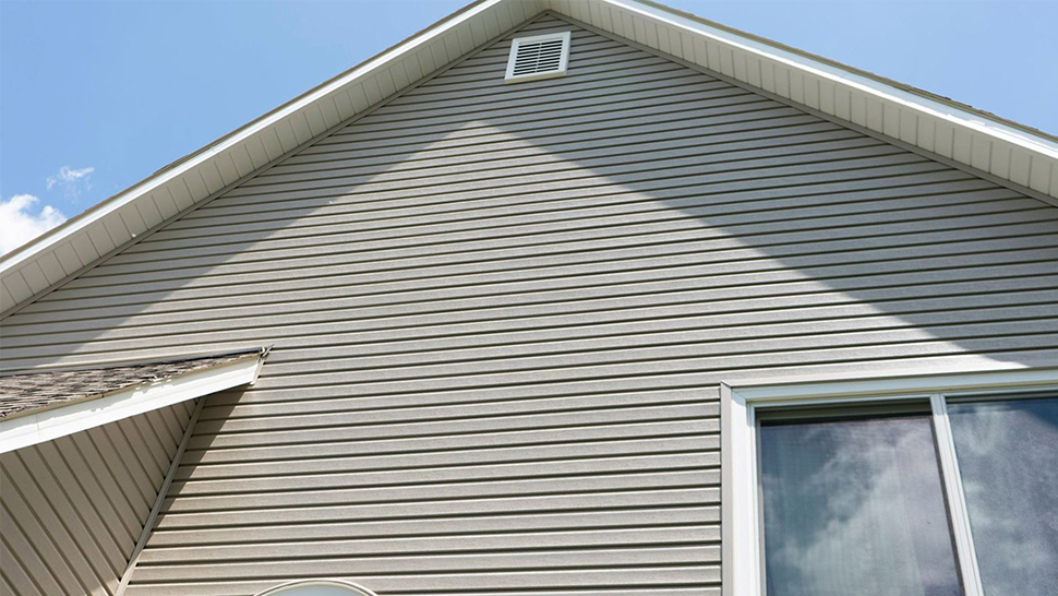 A house with a roof and a window with a blue sky in the background | Siefken Roofing and Remodeling Services in Omaha, NE