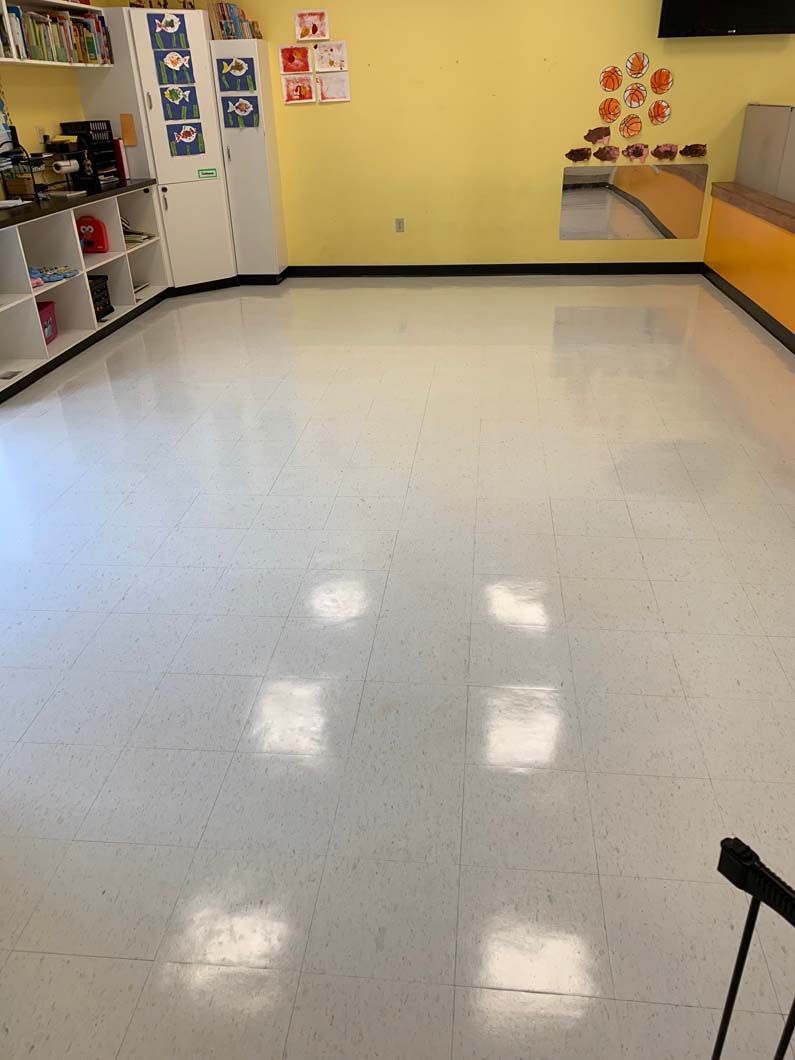 A bright room with yellow walls, white tiled floors, shelving on the left, and a decorative display on the back wall.