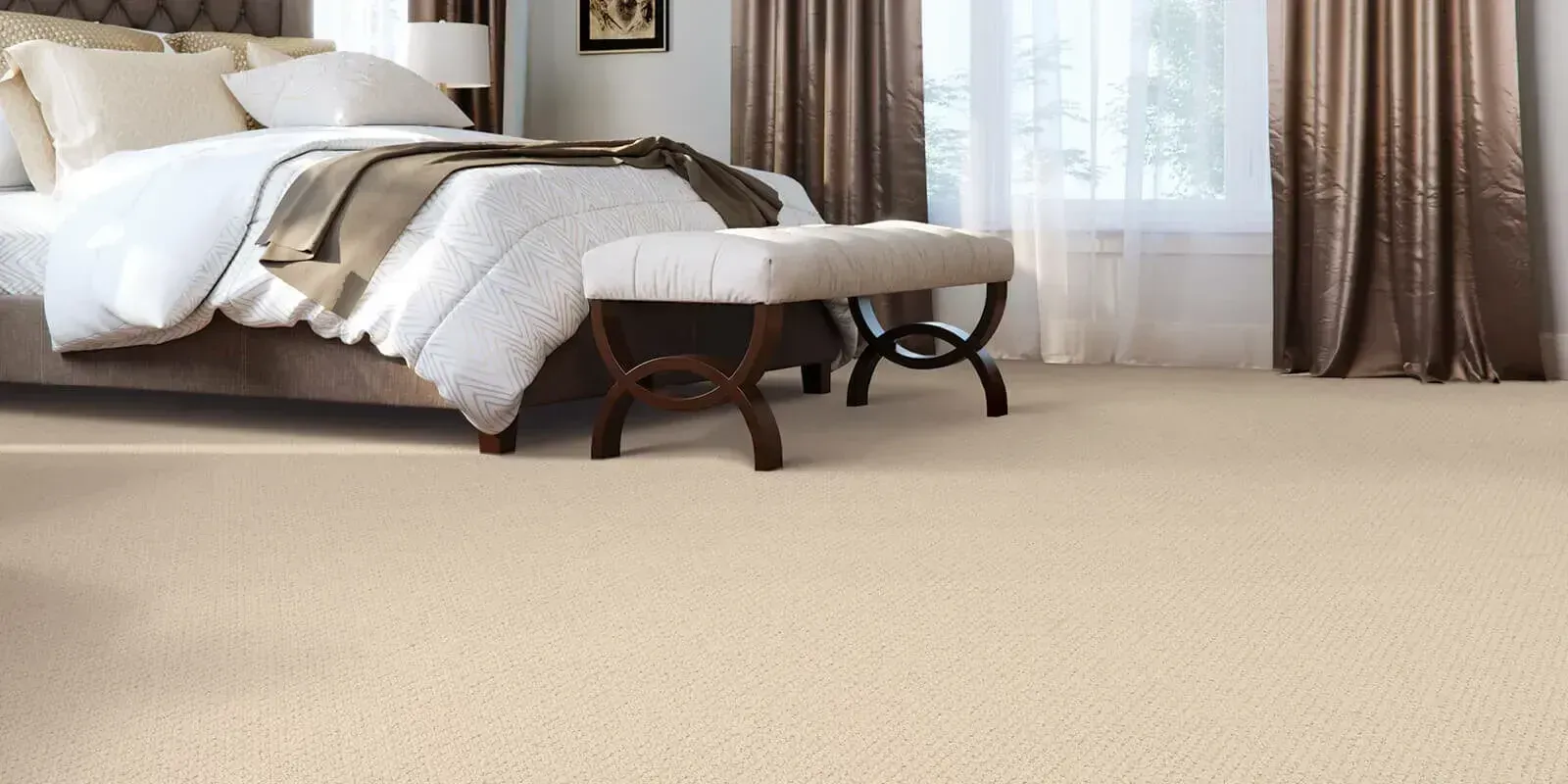 A bedroom featuring a bed with a white comforter, a small tufted bench, and beige wall-to-wall carpeting.