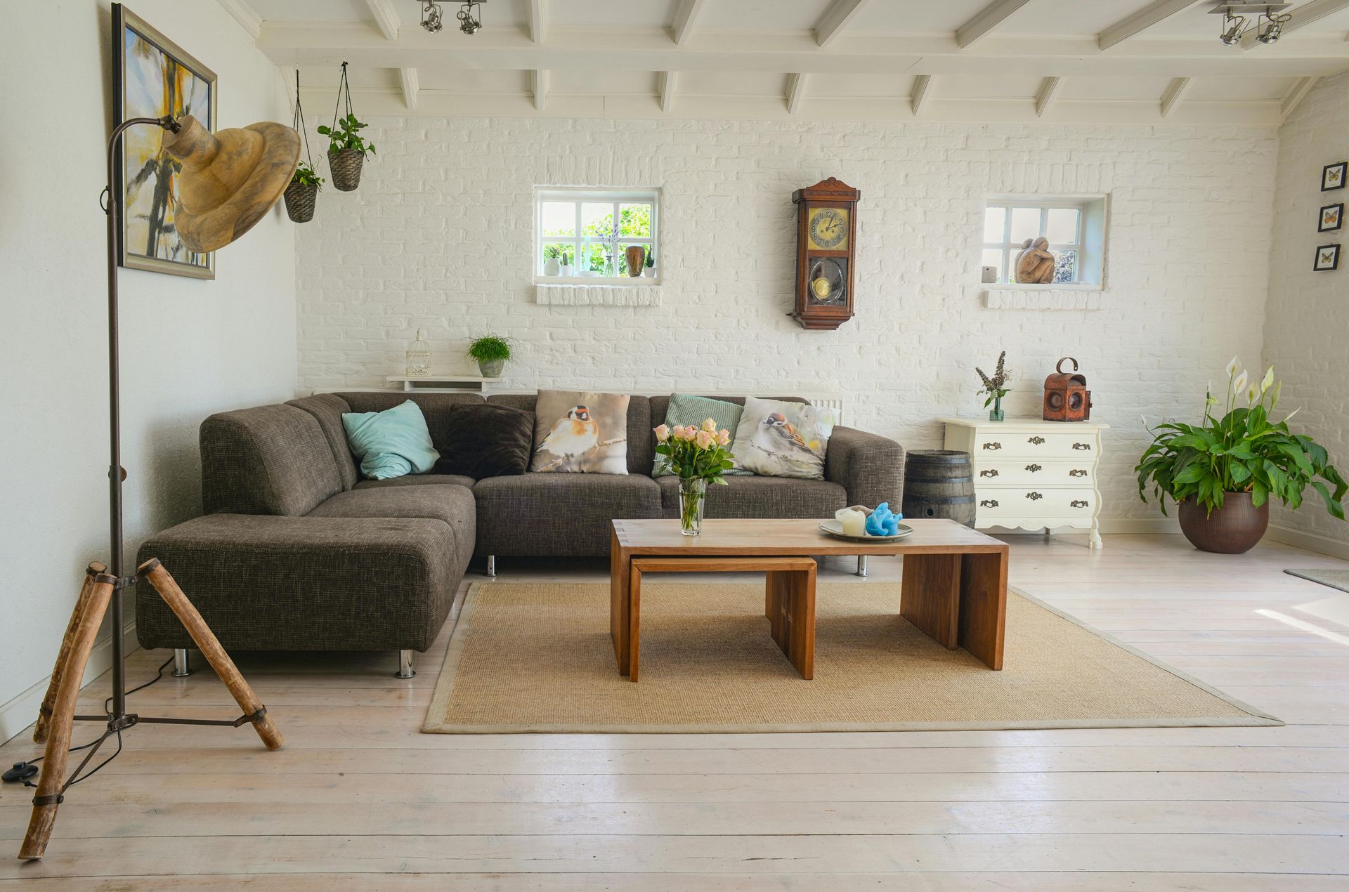 Cozy living room with brown sectional sofa, white brick walls, and wooden accents.