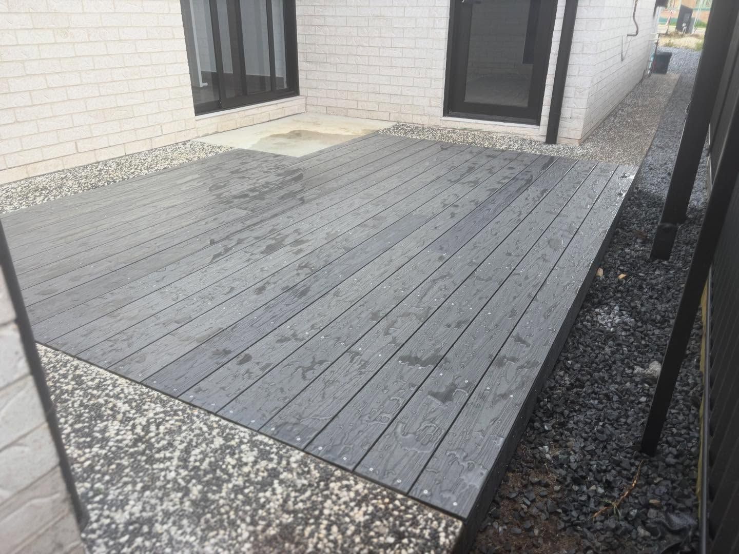 A Grey Composite Deck Located in the Backyard of a White Brick House — Coastbuilt Building Services in Thrumster, NSW