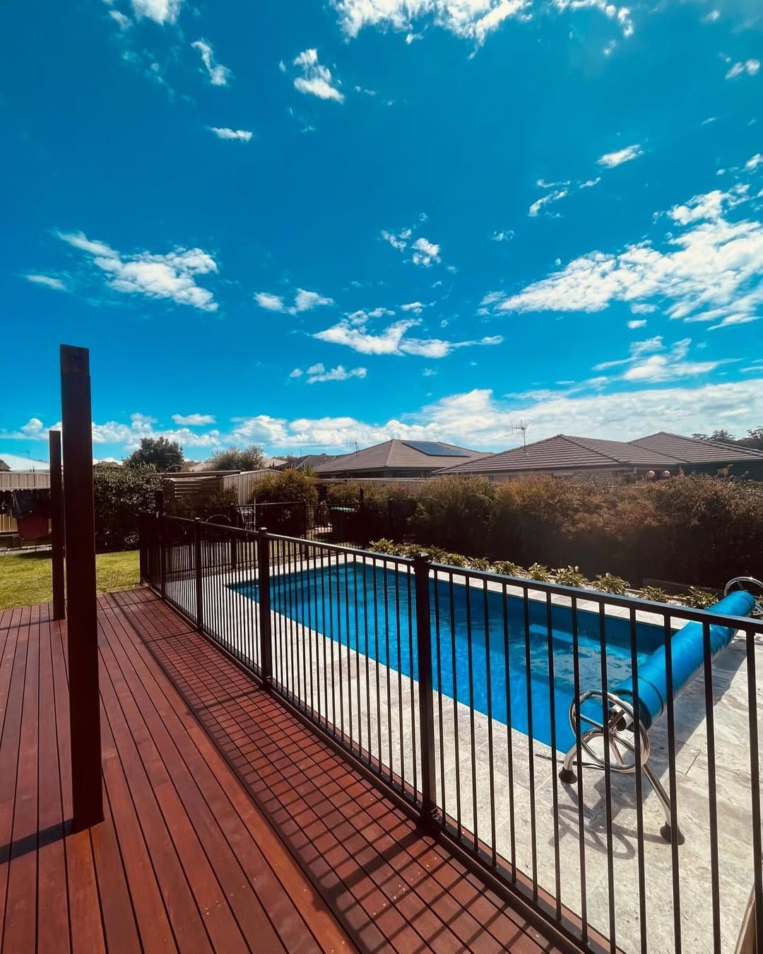 A Backyard Swimming Pool With a Blue Cover, Viewed From a Wooden Deck — Coastbuilt Building Services in Thrumster, NSW