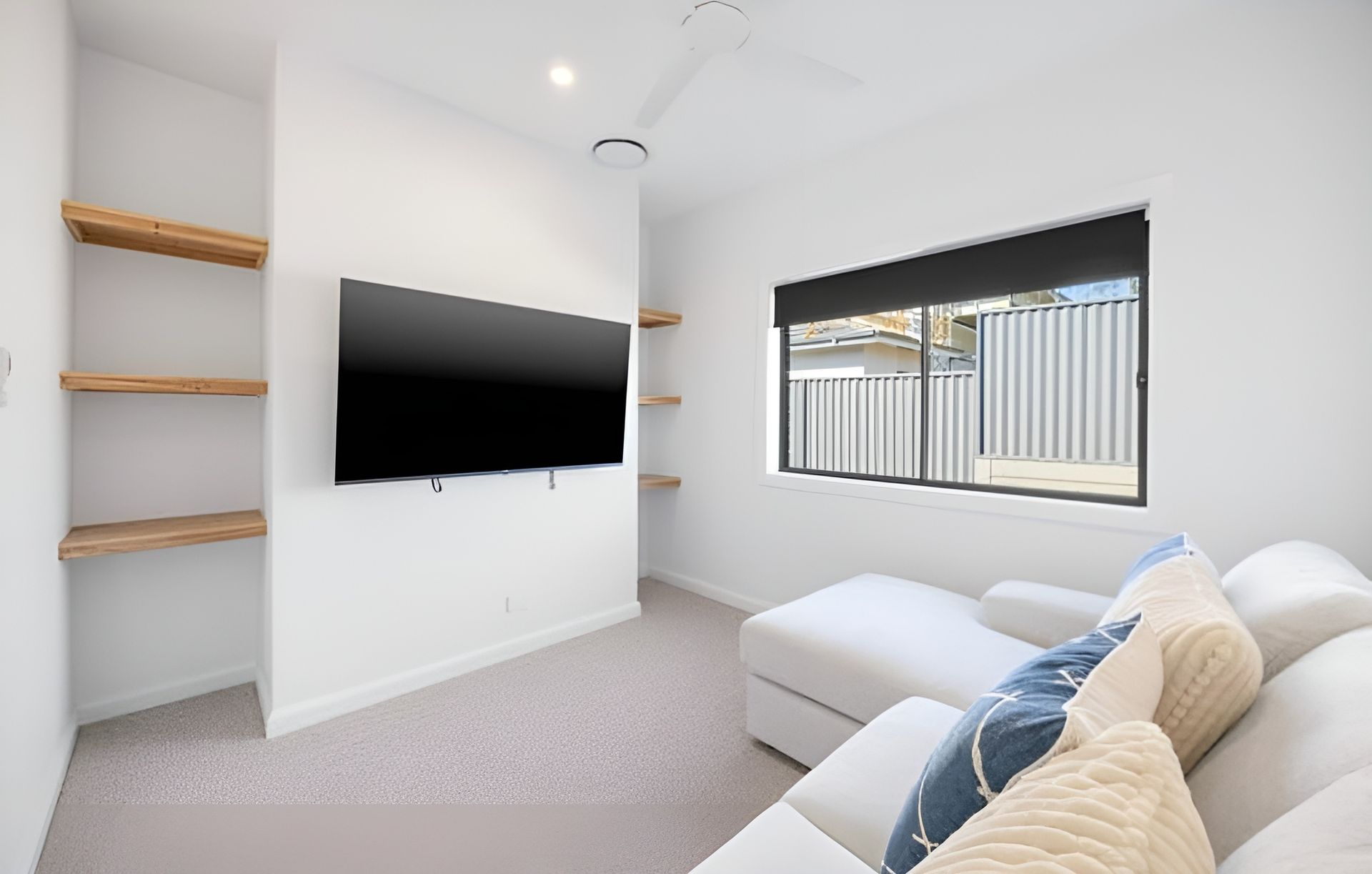 A Minimalist Room With a Mounted Television Between Built-in Wooden Shelves — Coastbuilt Building Services in Thrumster, NSW