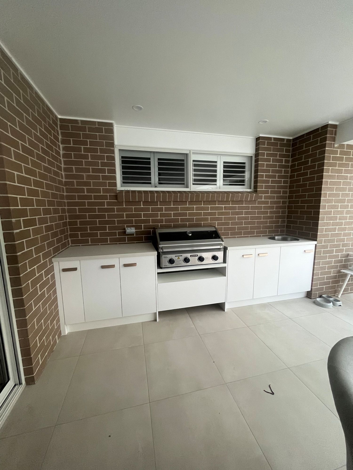 An Outdoor Kitchen With White Cabinets — Coastbuilt Building Services in Thrumster, NSW