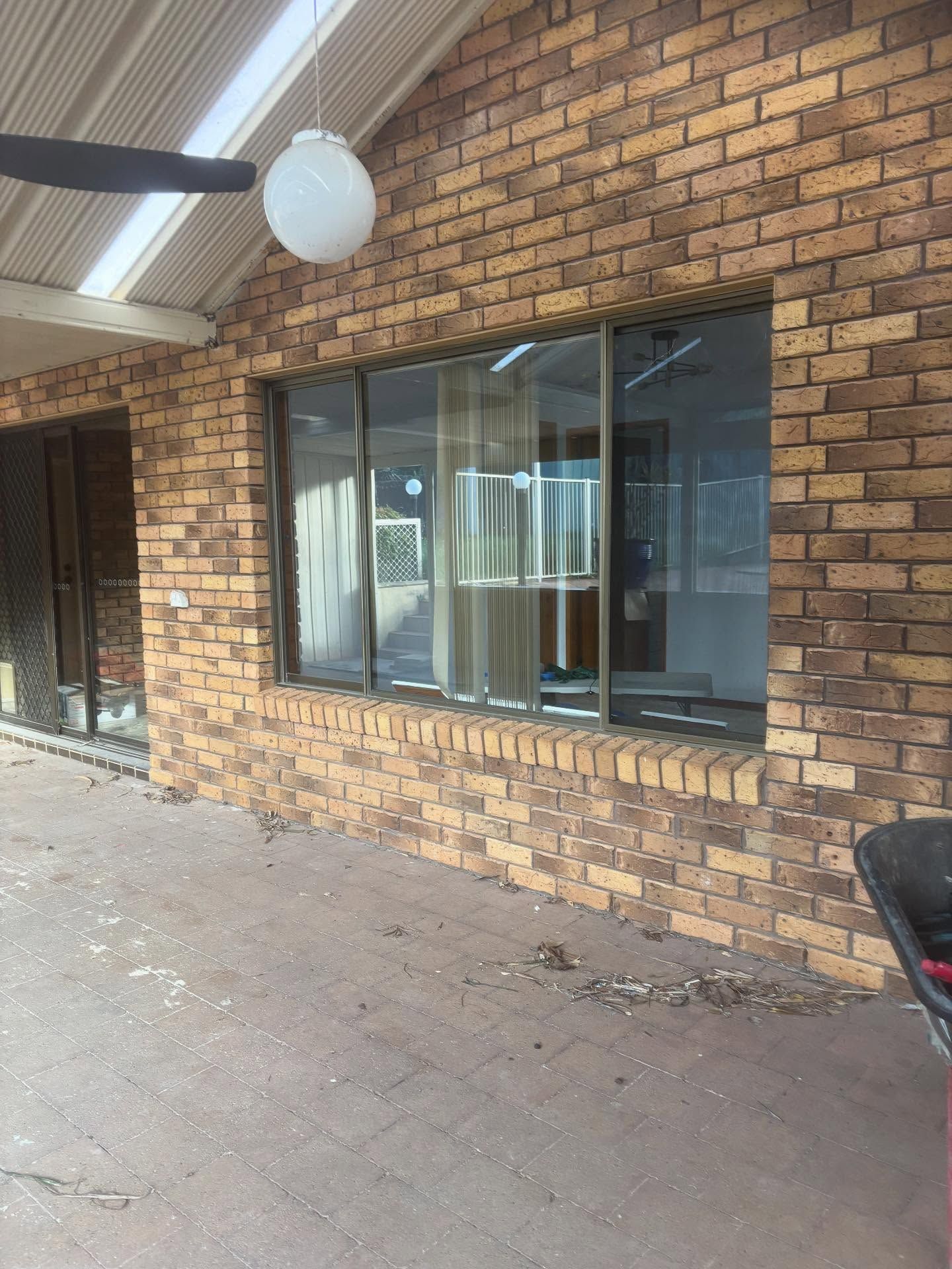 A Brown Brick Wall With a Large Window — Coastbuilt Building Services in Thrumster, NSW