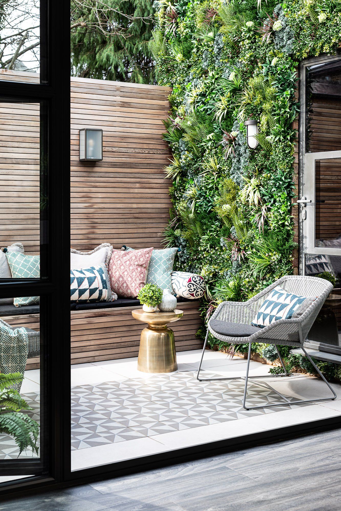 A patio with a bench , chair , table and plants.
