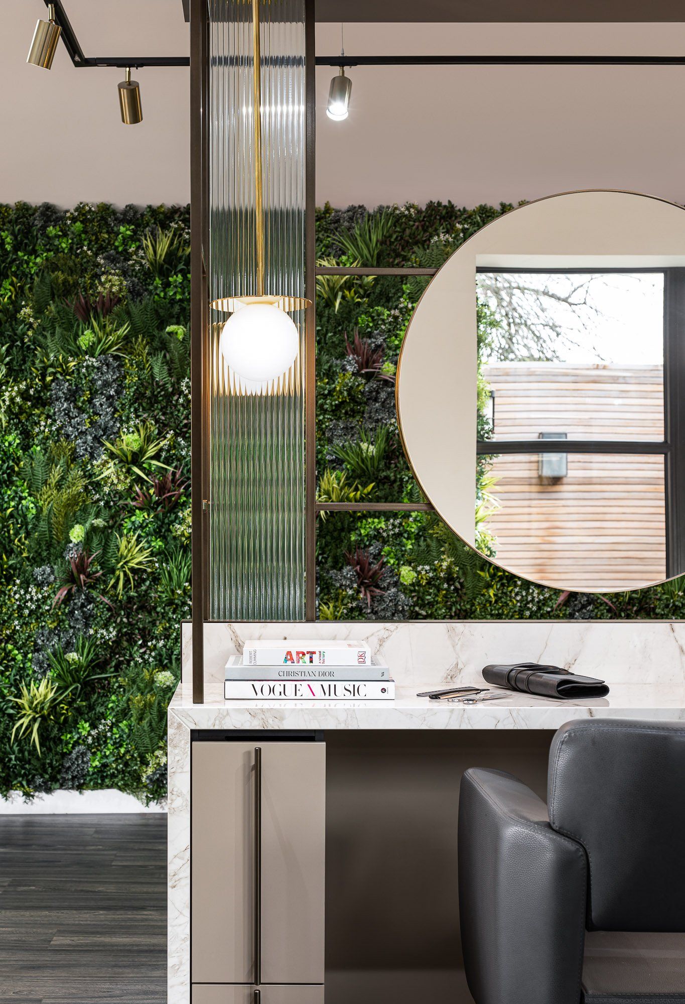 A hair salon with a green wall and a round mirror.