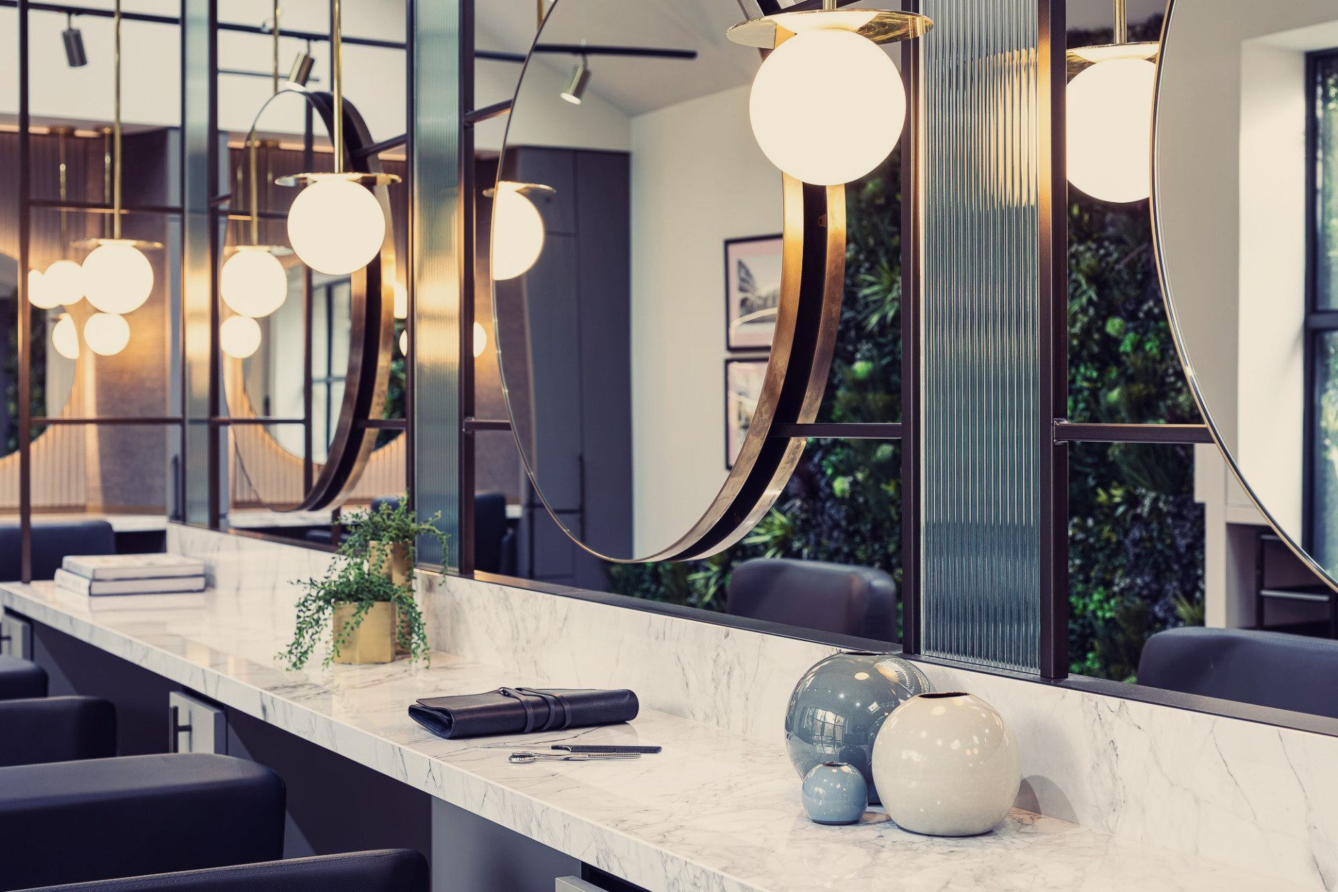 Leo Bancroft Modern salon interior with mirrors, globe pendant lights, and a marble countertop