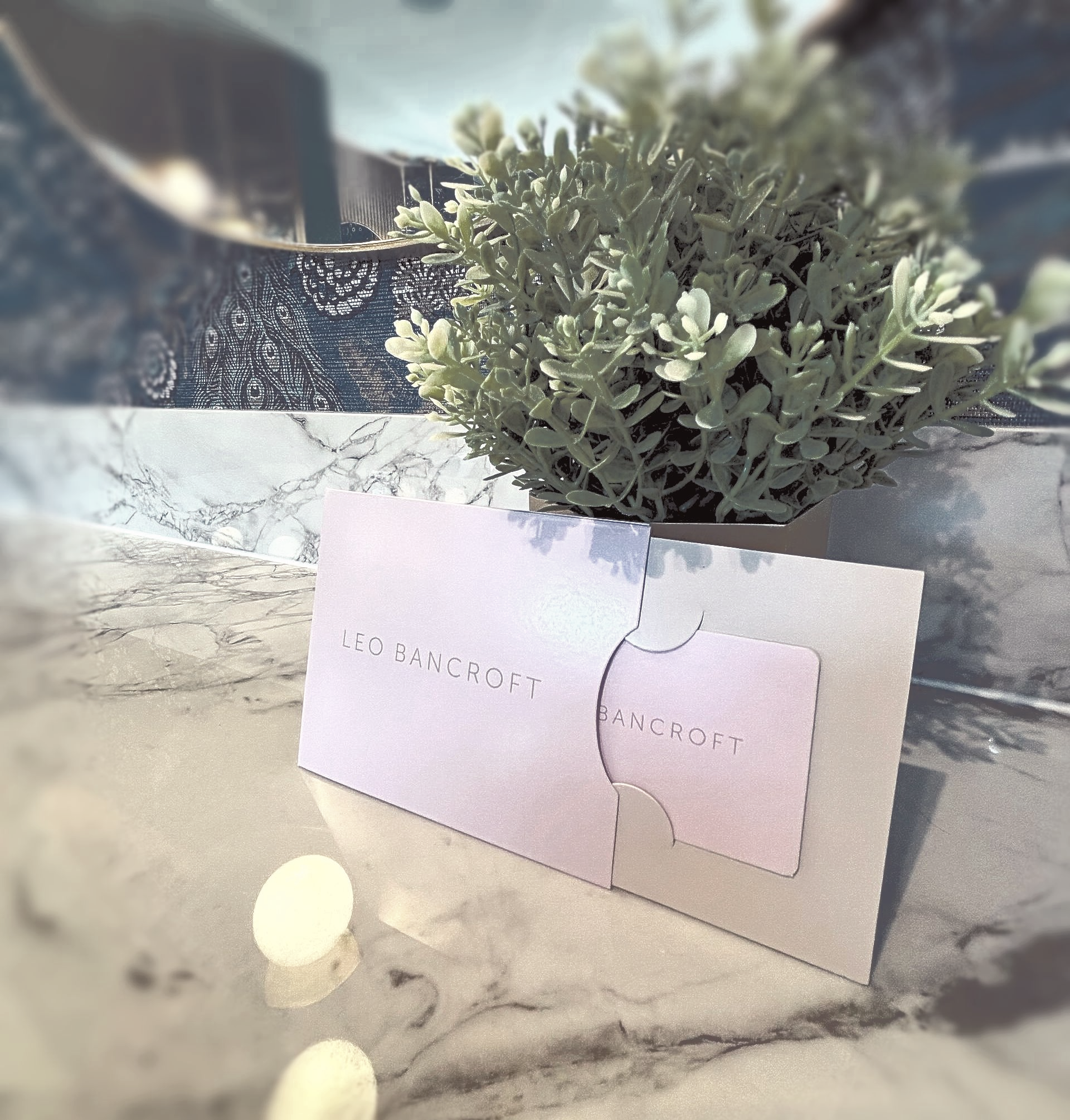 Pastel pink puzzle-piece card with a small plant on a marble table near a candle.