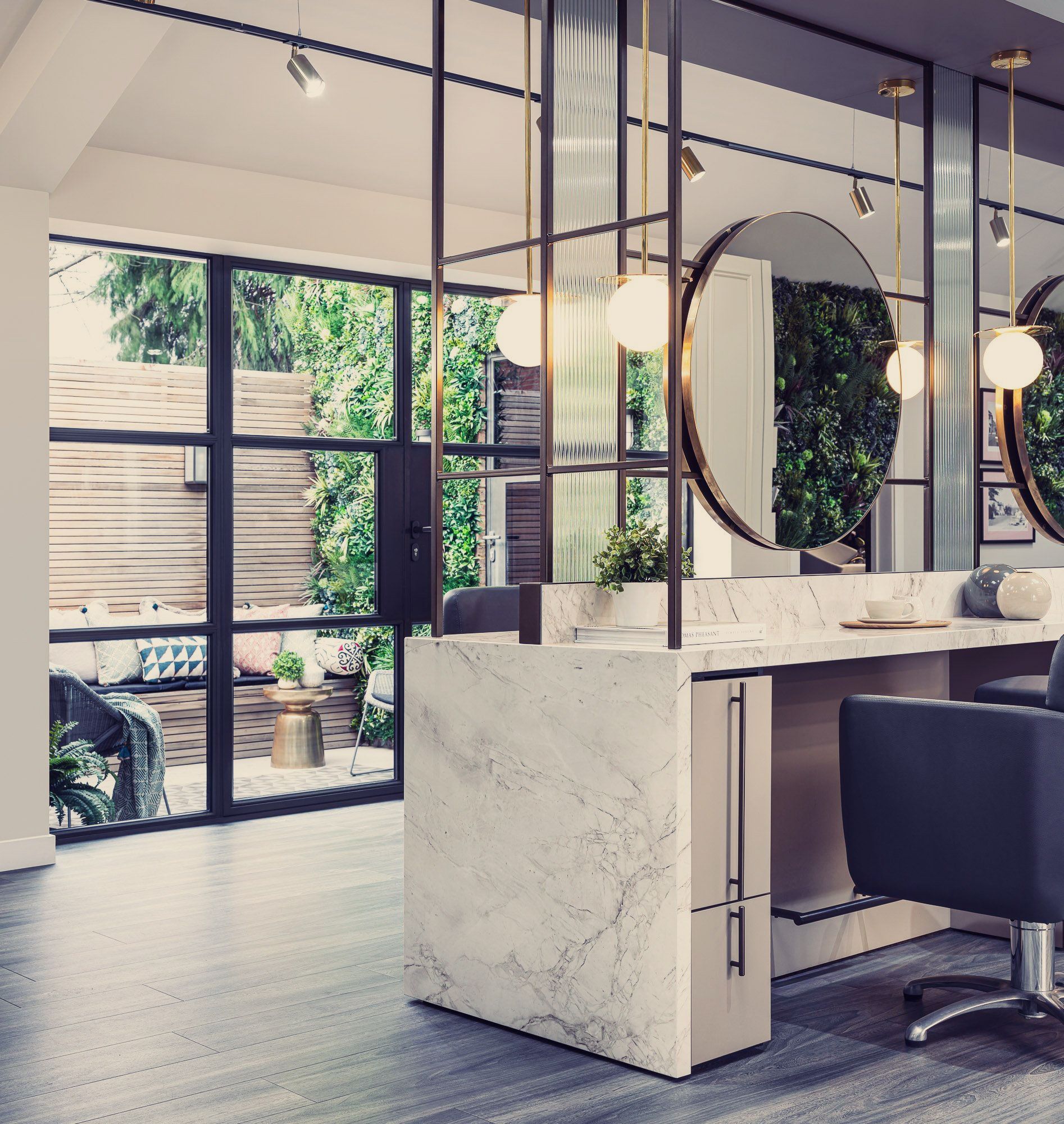Leo Bancroft Modern salon interior with marble styling station, round mirrors, pendant lights, and black chairs
