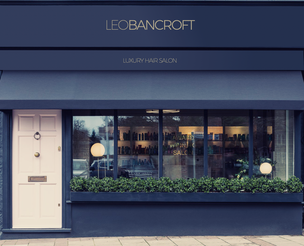 Leo Bancroft Blue storefront with “BANCROFT” sign, white door, and large window display with plants and hanging lights