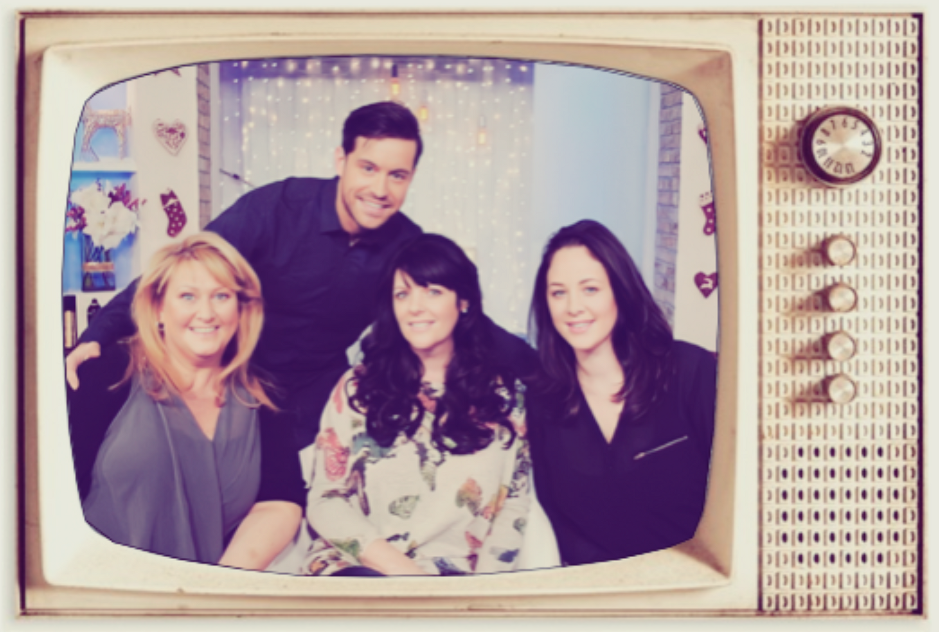 Four people posing inside a vintage TV frame, smiling in front of a lit backdrop.