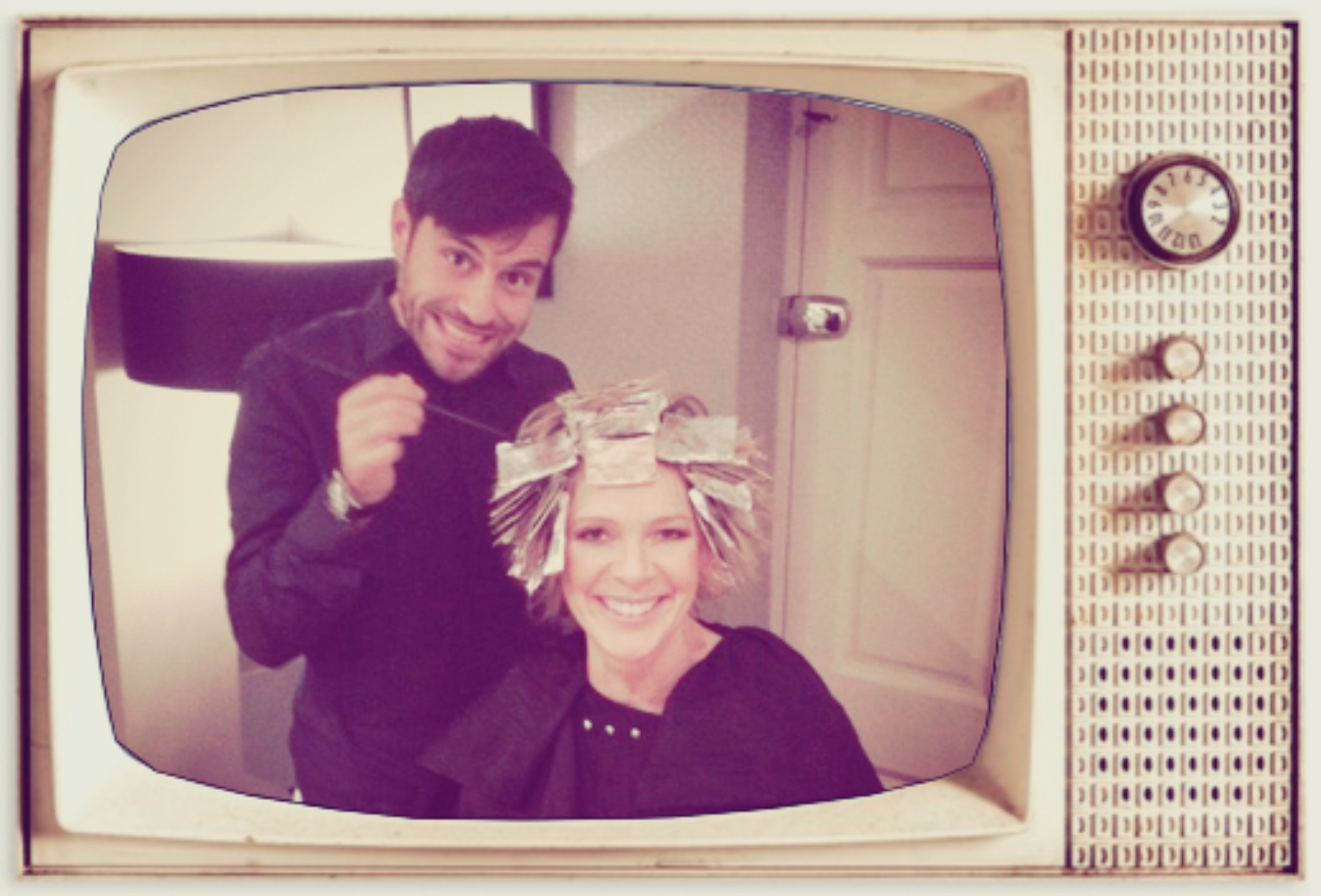 Two people smiling in a retro TV frame, with one styling the other's hair indoors