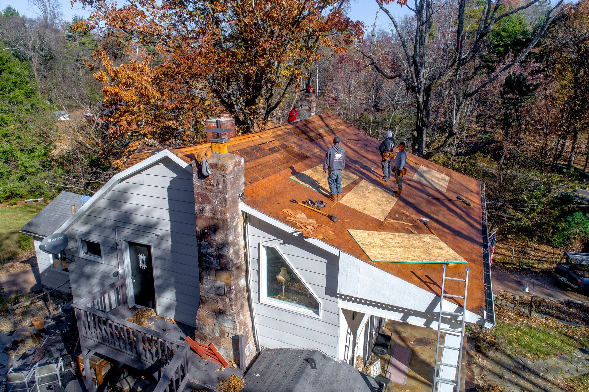 A group of people are working on the roof of a house