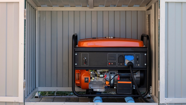 Portable generator in a storage shed with orange fuel tank and black frame