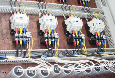 Electrical control panel with relays, wiring, and terminal blocks in a gray industrial enclosure