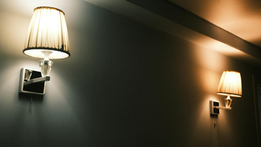 Two wall sconces with warm light on a dark hallway wall