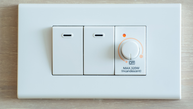 White wall switch panel with two switches and a dimmer knob on a light-colored plate