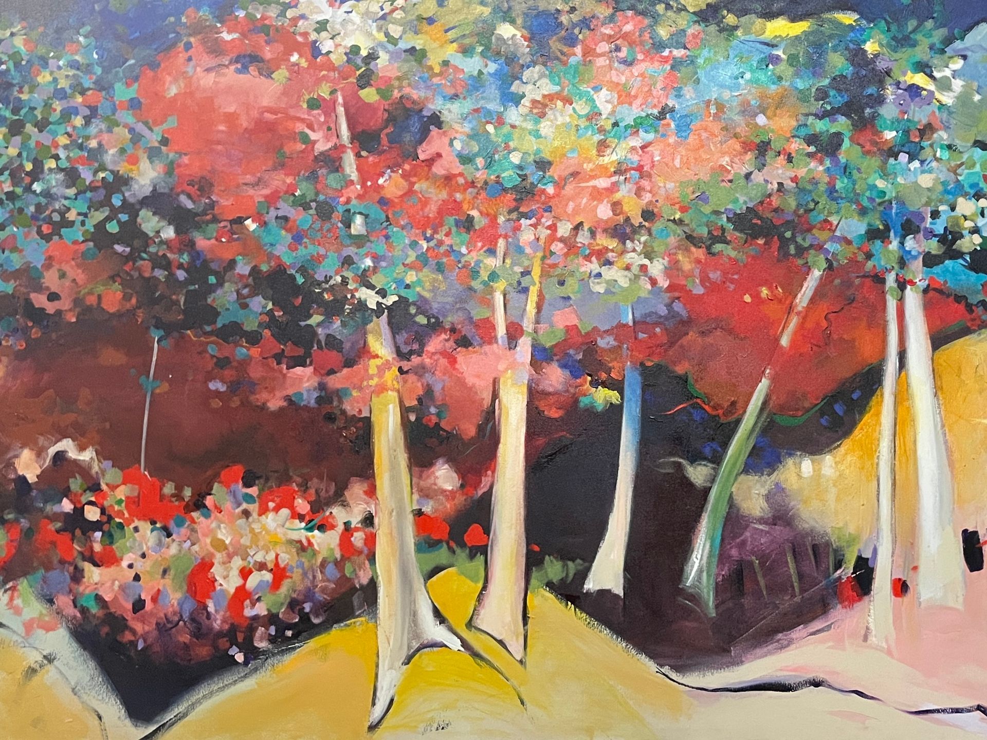 Colorful abstract painting of trees in a landscape. Reds, blues, and yellows dominate.