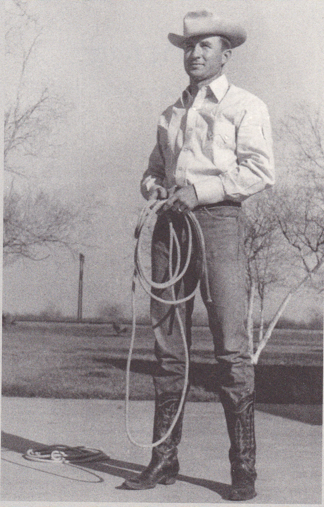 A man in a cowboy hat is holding a lasso